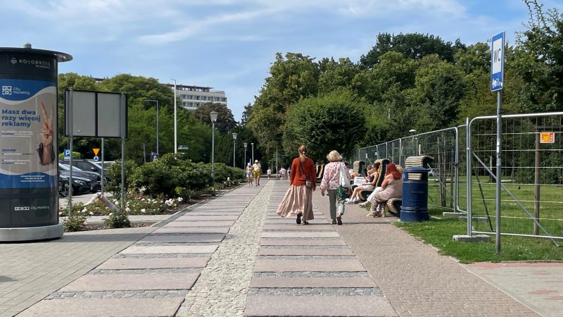 Ludzie spacerują po Kołobrzegu, inni siedzą na ławkach i odpoczywają