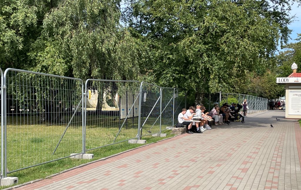 ludzie siedzą na ławkakch
