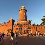 latarnia morska w Kołobrzegu, ludzie spacerują, chodzą wokół zabytku, siedzą