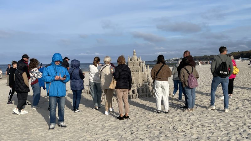 LUDZIE STOJĄ NA PLAży okół zamku z piasku
